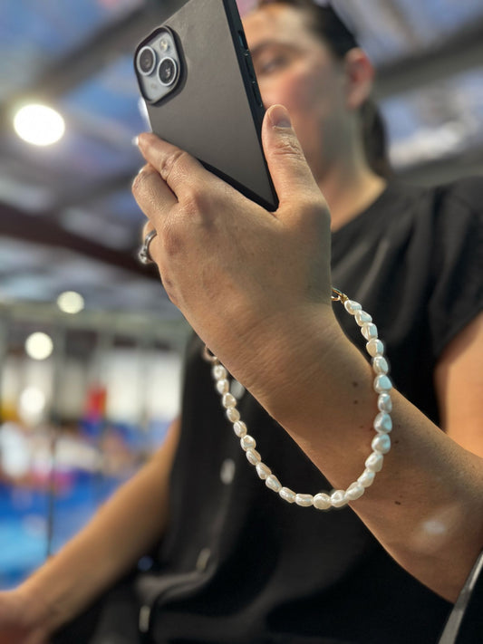 Close-up of a chic pearl phone wristlet, as seen on Netflix's Emily in Paris. This elegant accessory combines timeless style with modern functionality, perfect for adding a touch of Parisian flair to any outfit. Phone Accessory for any girl and any phone.