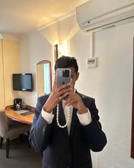 Person taking a mirror selfie in a room with a pearl-style phone case strap with gold clasps, elegant and detachable for a chic upgrade to any phone case or bag.