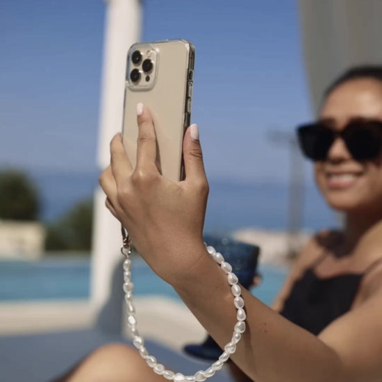 Close-up of a chic pearl phone wristlet, as seen on Netflix's Emily in Paris. This elegant accessory combines timeless style with modern functionality, perfect for adding a touch of Parisian flair to any outfit. Phone Accessory for any girl and any phone.