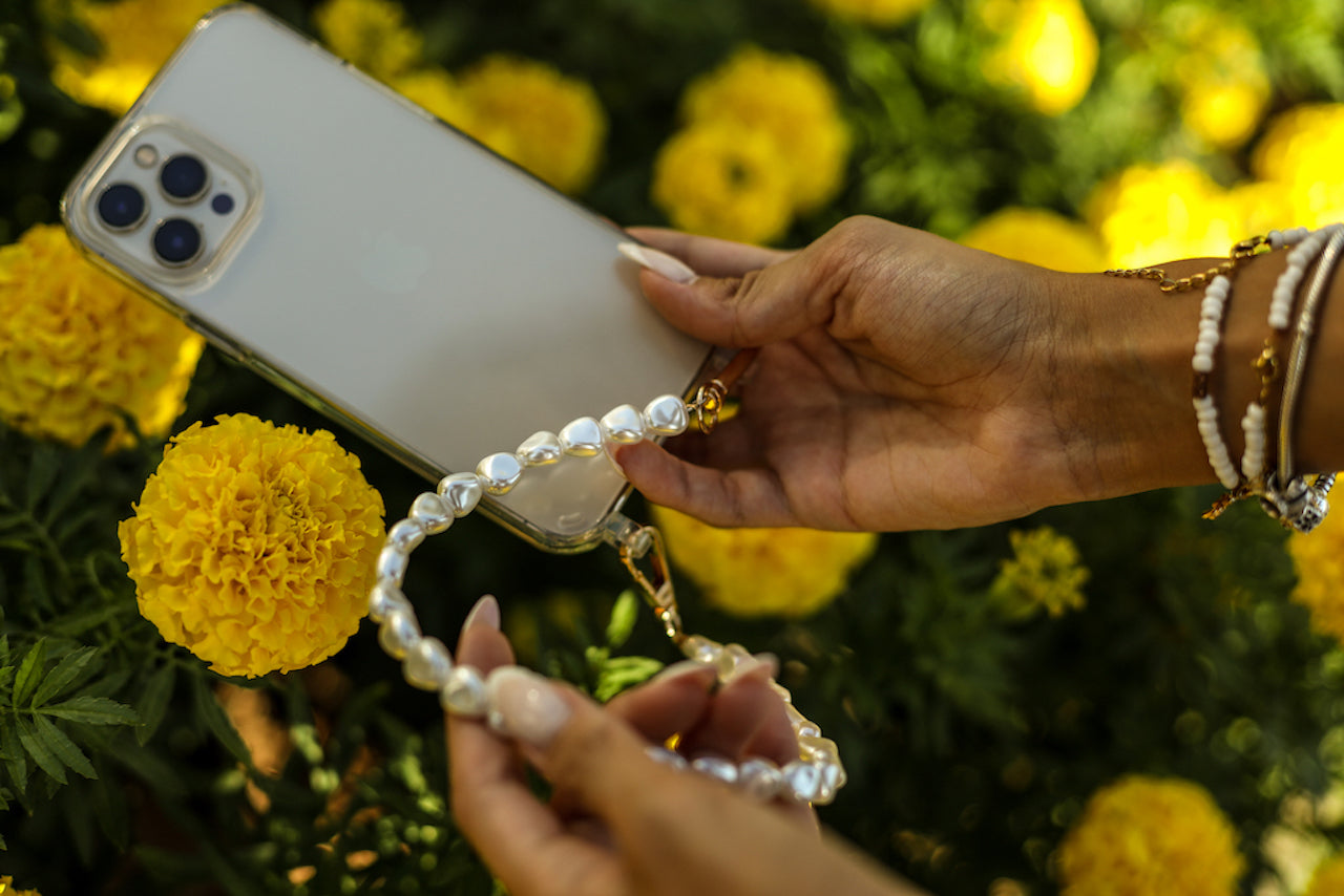 Close-up of a chic pearl phone wristlet, as seen on Netflix's Emily in Paris. This elegant accessory combines timeless style with modern functionality, perfect for adding a touch of Parisian flair to any outfit. Phone Accessory for any girl and any phone.